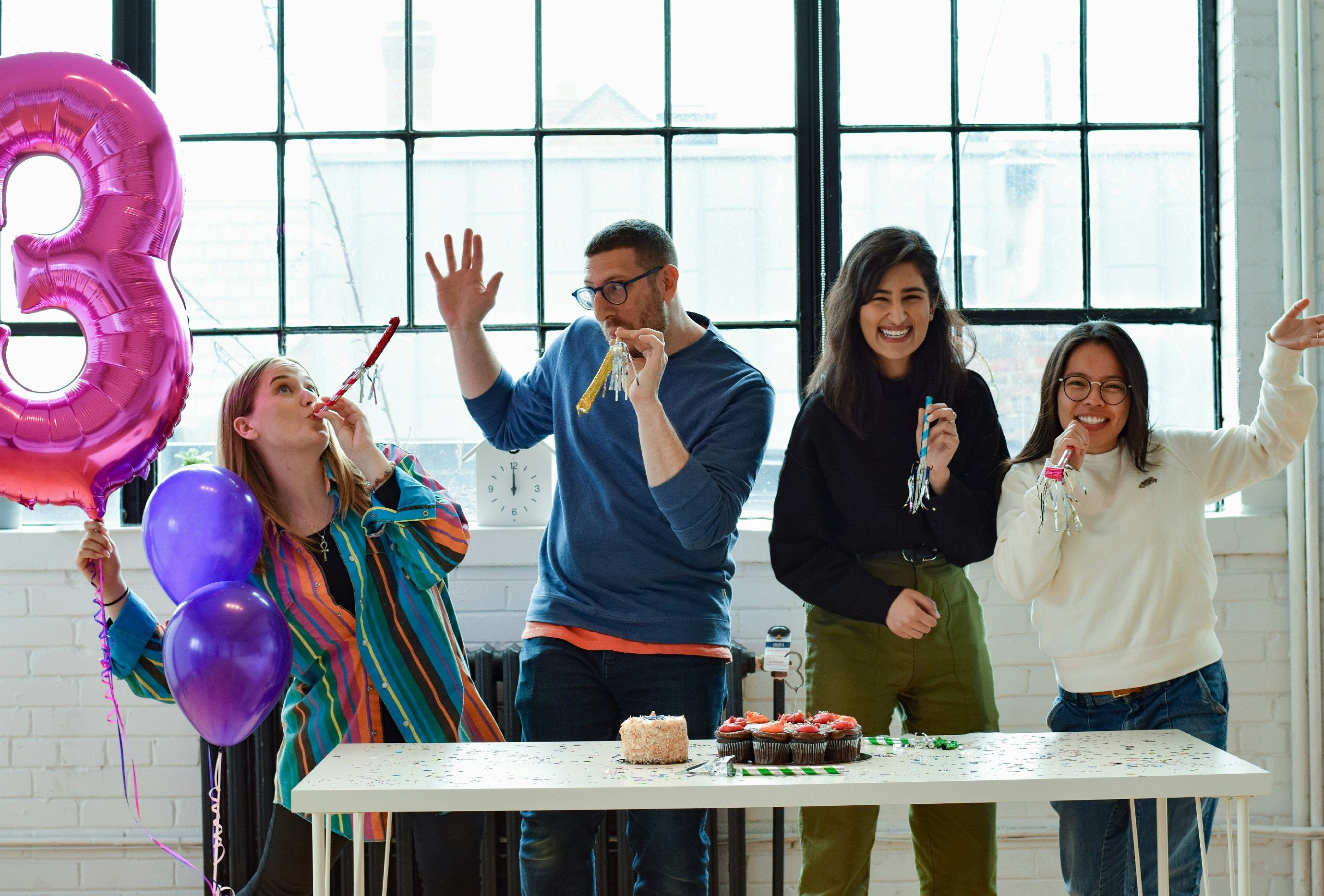 a group of people standing around a table with a cake