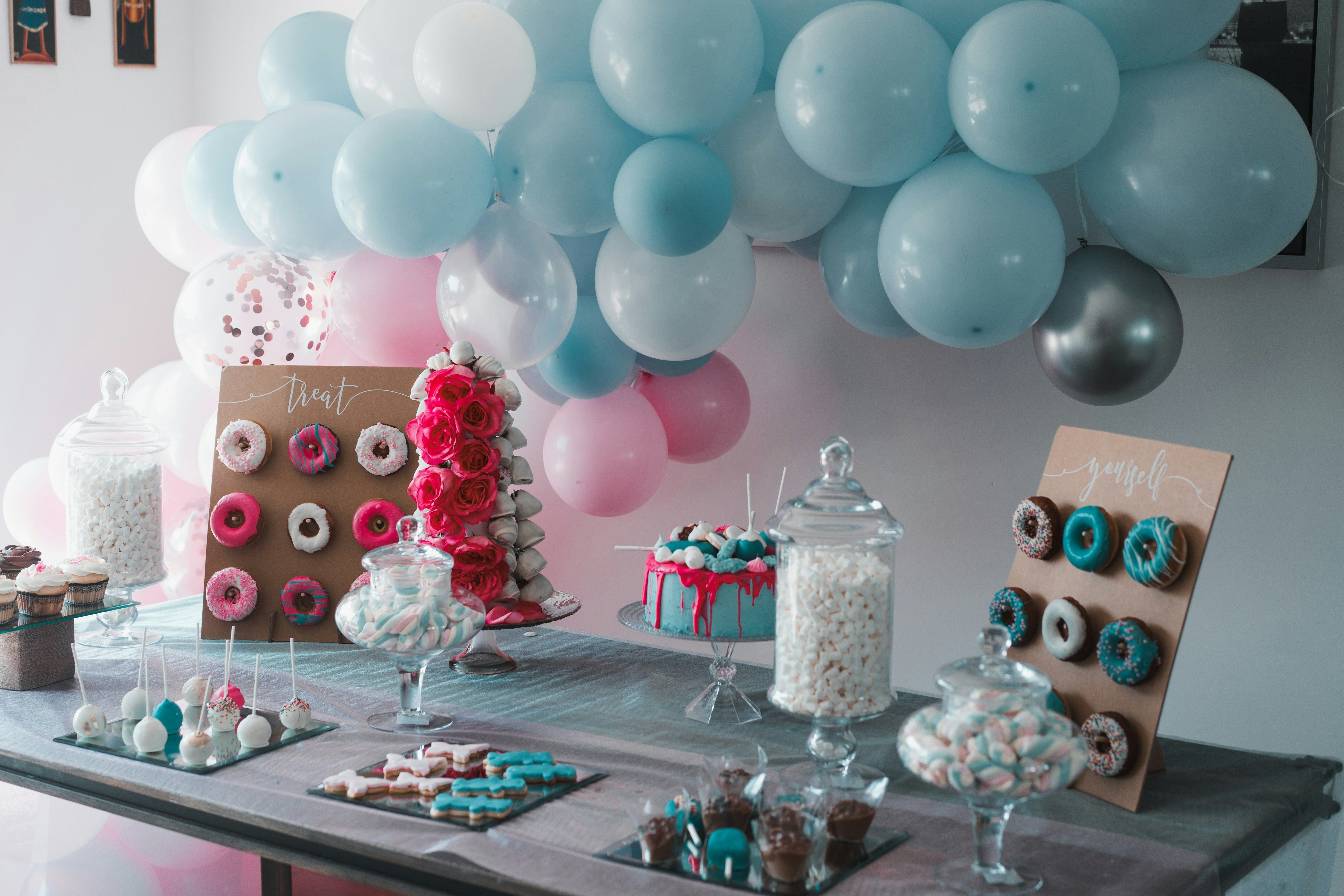 a table topped with lots of desserts and balloons
