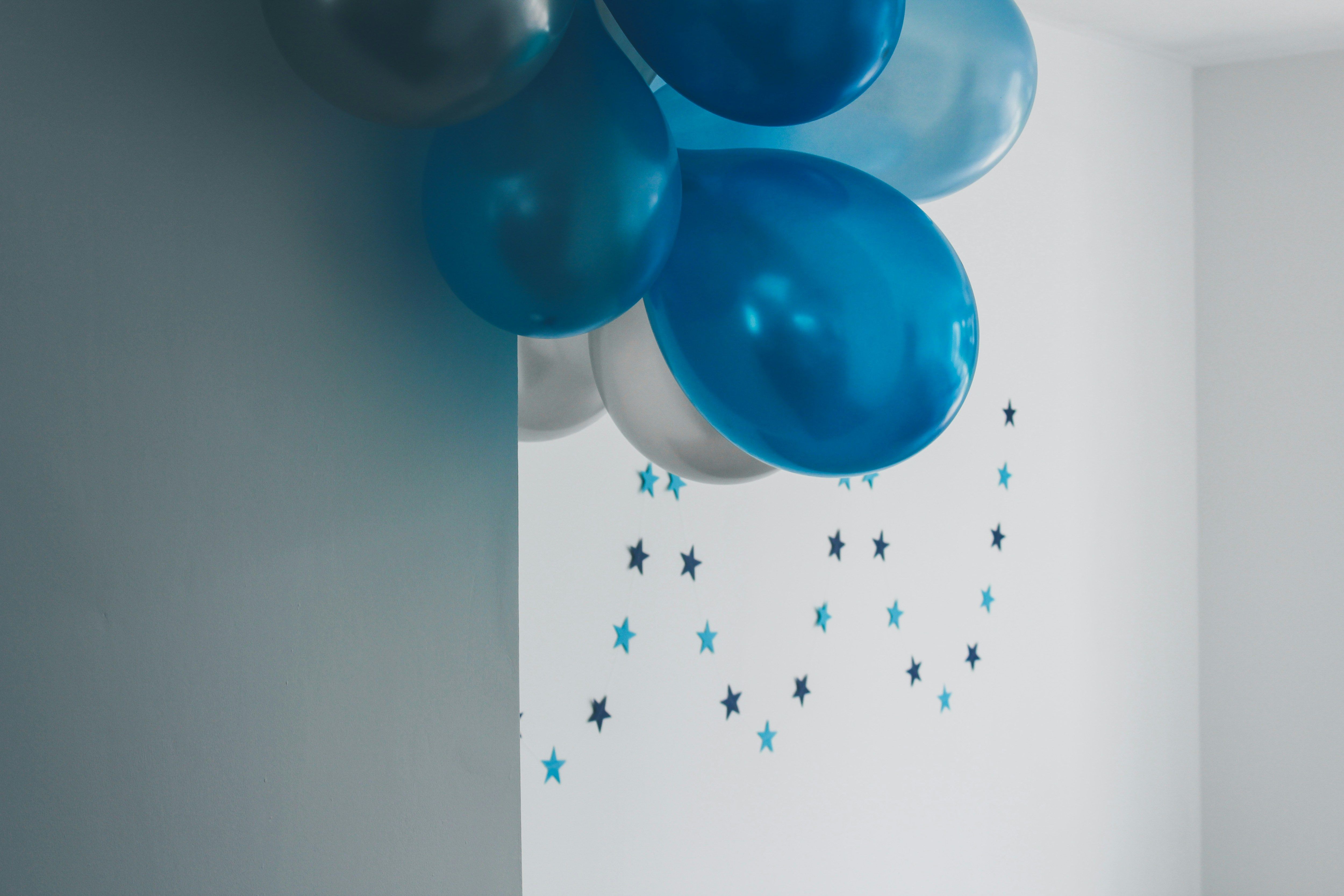 a bunch of blue and white balloons hanging from a wall