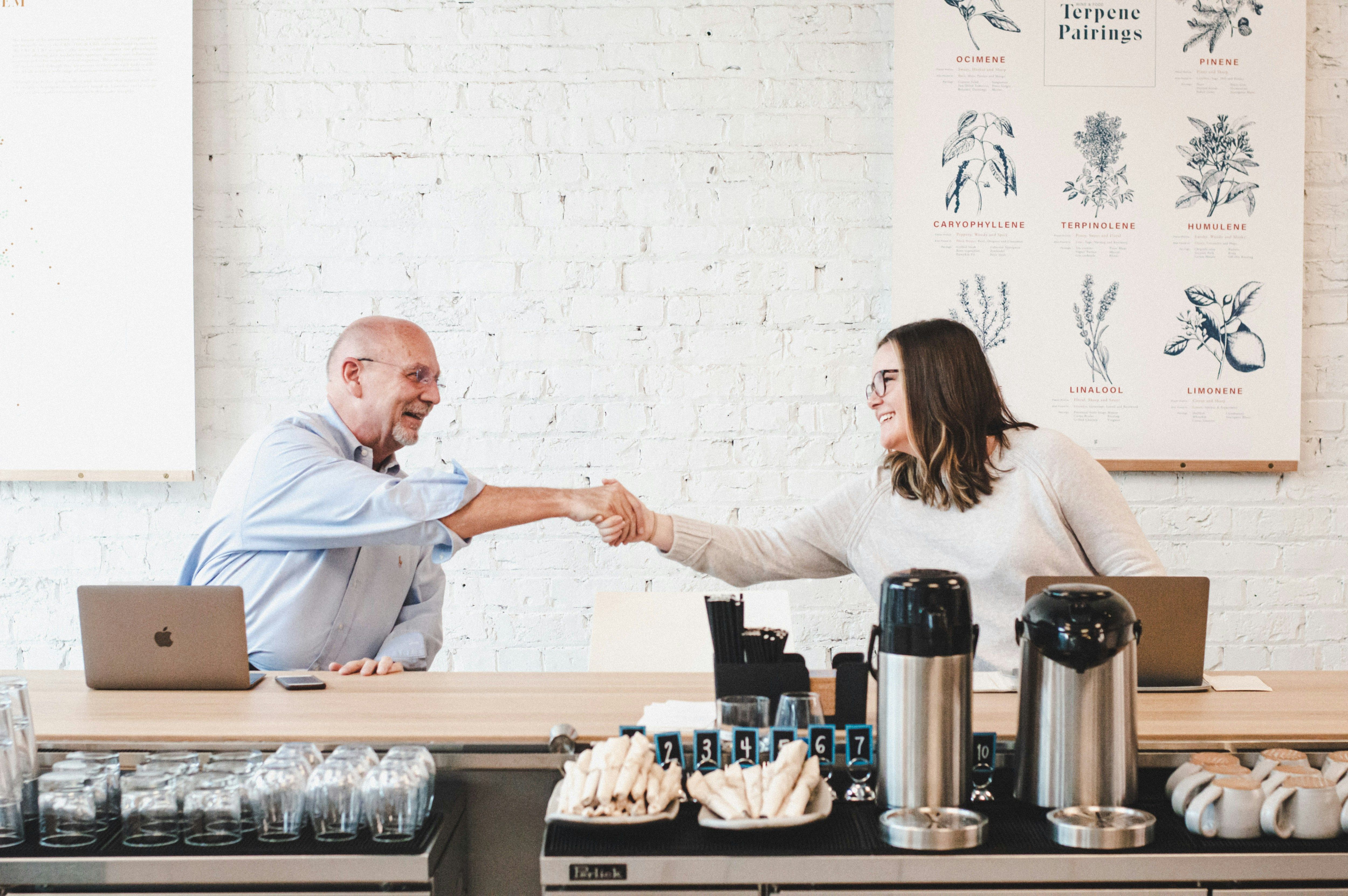 a man and woman shaking hands in front of a laptop